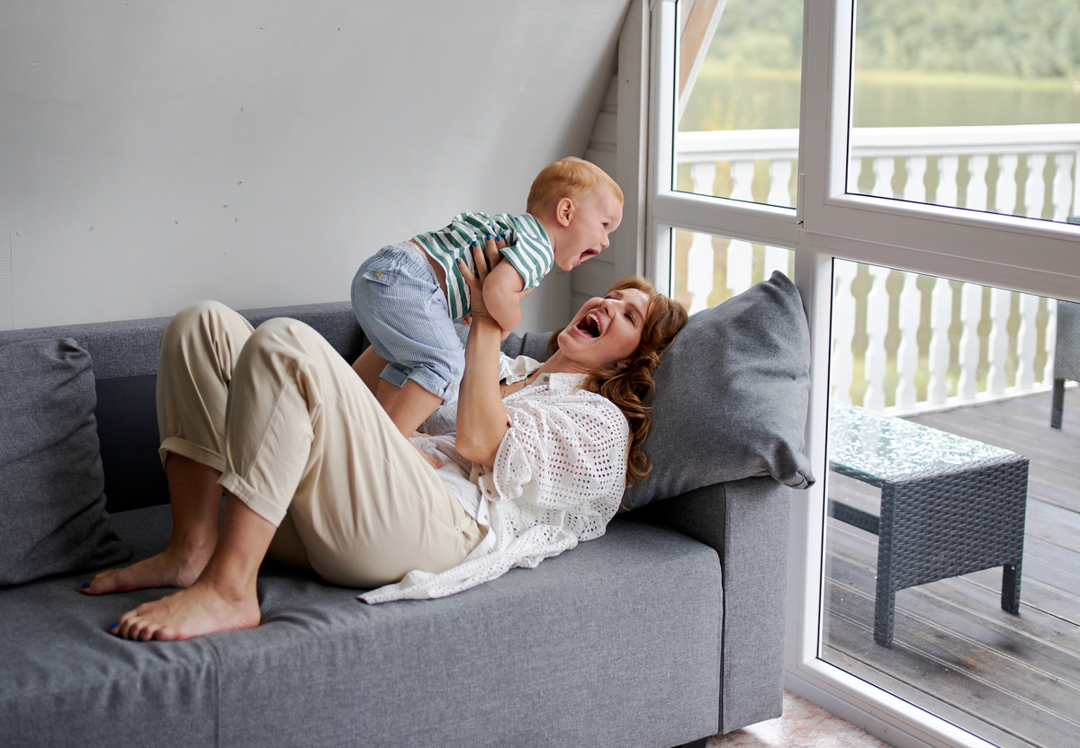 mom playing with toddler on couch